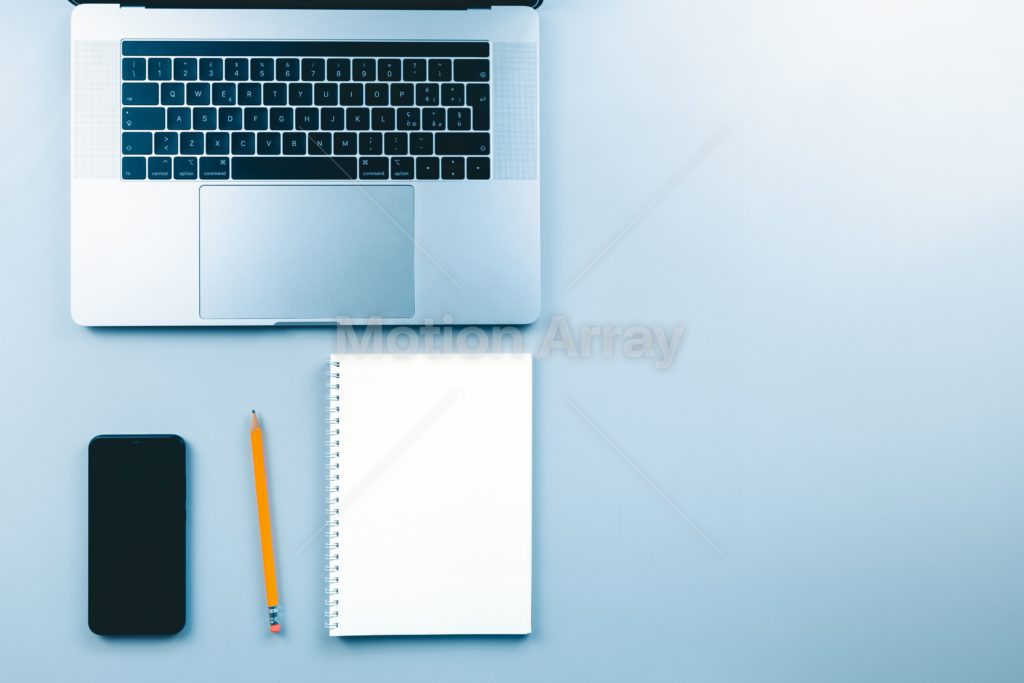 Office desk working space with a laptop, notepad, pencil and phone